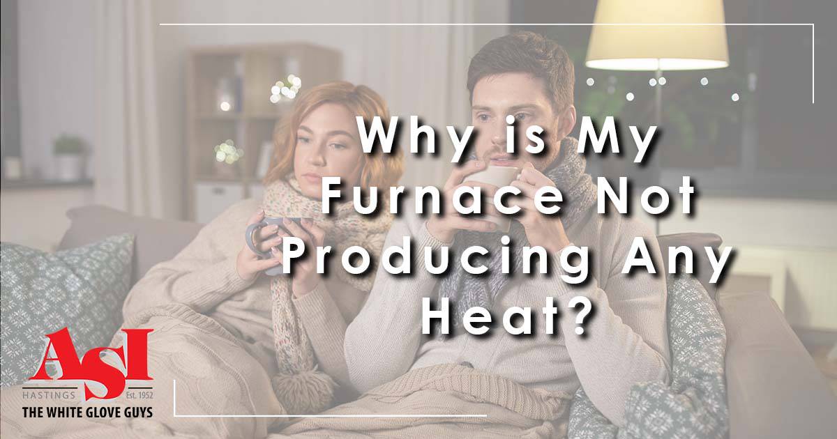 Image: a couple on a couch bundled up because their heating isn't working, cover image for Why is My Furnace Not Producing Any Heat?