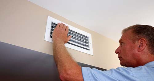 Image: a man checking his vents.