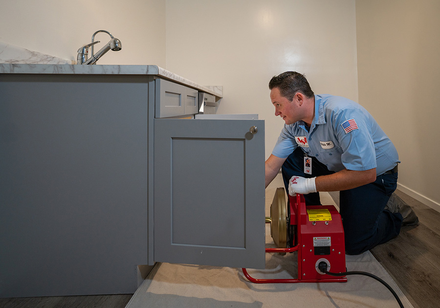 Plumber using tools to investigate a plumbing issue